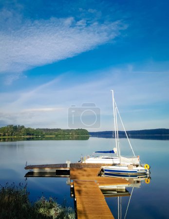 Photo for Sailing on Lake Wdzydze. A sailboat moored at the shore of the lake. Wdzydze is one of the largest Polish lakes. It is located in the Tucholskie Forests in Northern Poland. - Royalty Free Image