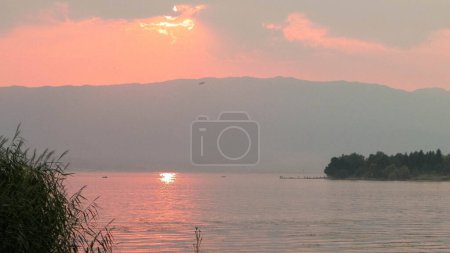 Beautiful sunset over Ochrid lake. Reflection of the sun in the beautiful water of Lake Ochrid. Ochrid is the oldest lake in Europe. Travel and beauty in nature concept.