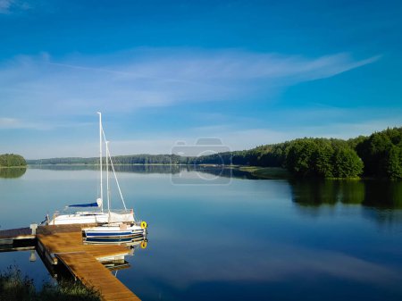 Sailing on Lake Wdzydze. A sailboat moored at the shore of the lake. Wdzydze is one of the largest Polish lakes. It is located in the Tucholskie Forests in Northern Poland.