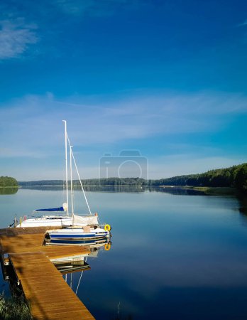 Photo for Sailing on Lake Wdzydze. A sailboat moored at the shore of the lake. Wdzydze is one of the largest Polish lakes. It is located in the Tucholskie Forests in Northern Poland. - Royalty Free Image