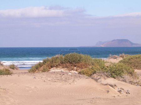 Beach, Atlantic Ocean and La Graciosa island in Caleta de Famara, Lanzarote Canary Islands. Beach in Caleta de Famara is very popular among surfers. Copy space.