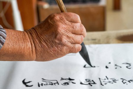 Téléchargez les photos : Un vieux calligraphe chinois écrit des personnages de calligraphie, crée des œuvres de calligraphie - en image libre de droit