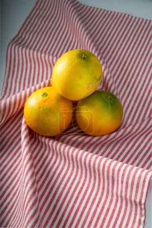 Foto de Primer plano de las naranjas sobre fondo de mantel rayado rojo - Imagen libre de derechos