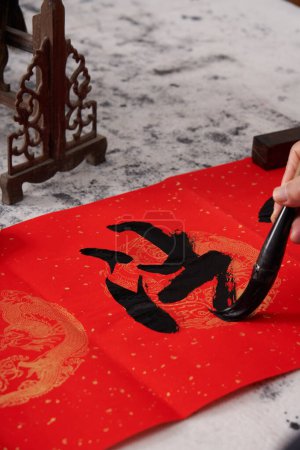Téléchargez les photos : Un vieux calligraphe écrit des couplets au cours de l'Année chinoise du Dragon.Traduction : Le cheval caressant accueille le printemps avec allégresse. - en image libre de droit