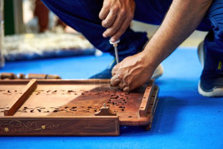 A worker is installing traditional Chinese wooden furniture