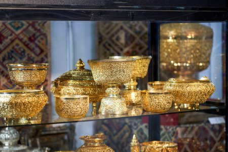 Recipientes y utensilios de oro de estilo sudeste asiático colocados en el gabinete