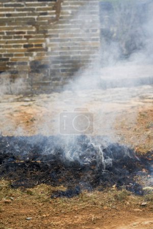 A pile of burning straw outdoors in the countryside