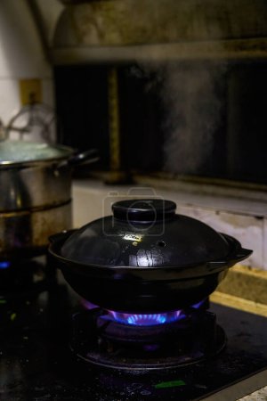 Claypot dishes are being cooked on the stove in a Chinese kitchen