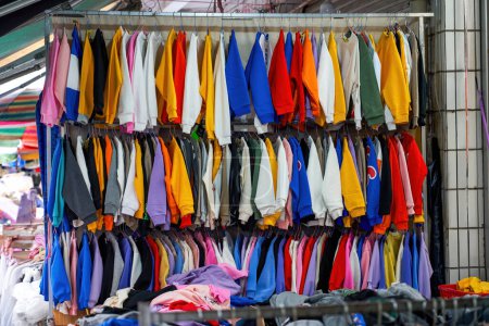 A variety of clothing and clothing for sale in a lively flea market