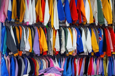 A variety of clothing and clothing for sale in a lively flea market