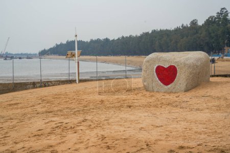 Foto de Una romántica piedra con un corazón rojo grabado en la playa junto al mar - Imagen libre de derechos