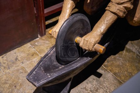 Close-up of a sculpture of a pharmacy clerk grinding medicine using a grinding stone