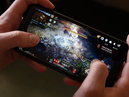 Téléchargez les photos : Cork, Ireland, July 31, 2022. A android smartphone in the hands of a white man. Playing mobile MMORPG Black Desert Mobile. A Korean mobile game on a smartphone screen, illustrative editorial. - en image libre de droit