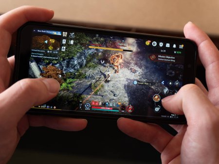 Téléchargez les photos : Cork, Ireland, July 31, 2022. A smartphone in the hands of a white man. Playing mobile MMORPG Black Desert Mobile. A Korean mobile game on a smartphone screen, illustrative editorial. - en image libre de droit