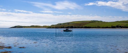 Téléchargez les photos : County Cork, Ireland, August 21, 2022. One small fishing boat on a calm water surface near the hilly Irish coast on a sunny summer day. boat, water - en image libre de droit