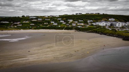 Photo for The famous Irish beach of Inchydoney at low tide, top view. Houses on the seashore. Huge sandy beach. Overcast gray sky. A small coastal settlement. - Royalty Free Image