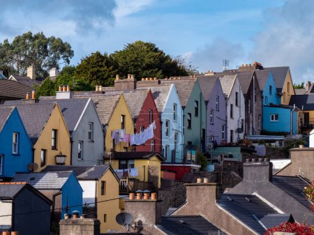 Foto de Casas europeas multicolores a lo largo de la calle de la pequeña ciudad irlandesa de Cobh, paisaje urbano. Cielo azul sobre la ciudad. Casas, cielo azul - Imagen libre de derechos