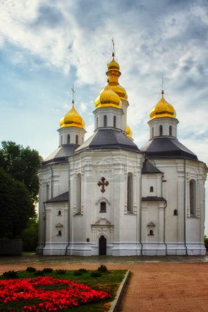 Die alte orthodoxe Katharinenkirche in Tschernihiw mit ihrer weißen Fassade und den ikonischen goldenen Kuppeln harmoniert wunderbar mit dem ruhigen blauen Himmel.