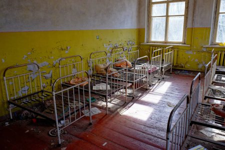 Téléchargez les photos : Cadres de lit en métal dans une pièce délabrée. Vieux lits d'enfants dans un jardin d'enfants abandonné. L'intérieur d'une pièce dans l'un des bâtiments de la zone d'exclusion radioactive de Tchernobyl. - en image libre de droit