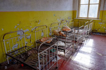 Téléchargez les photos : Une chambre abandonnée avec des cadres de lit en métal rouillé. Lits d'enfants dans un jardin d'enfants abandonné. L'intérieur d'une pièce dans l'un des bâtiments de la zone d'exclusion radioactive de Tchernobyl. - en image libre de droit