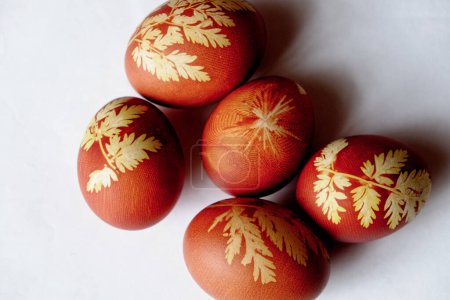 Reddish eggs adorned with yellow leaf designs.