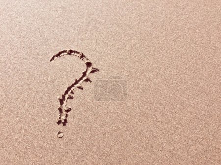 A question mark is etched into a sandy surface, symbolizing inquiry.