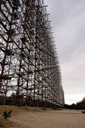 Amidst dry grass, an intricate metal tower extends into the sky showcasing detailed engineering work. Duga is a Soviet over-the-horizon radar station for an early detection system for ICBM launches.