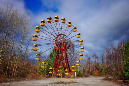 The image shows an unused, rusty Ferris wheel with yellow cabins.