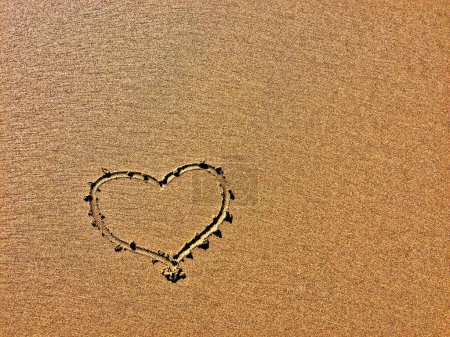 La imagen muestra una forma de corazón dibujada en la arena con granos finos.