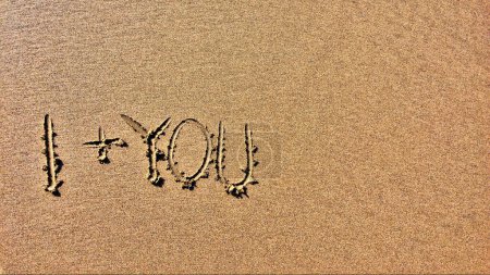 Eine sandige Oberfläche trägt die Inschrift I + YOU, was auf ein romantisches Gefühl hindeutet