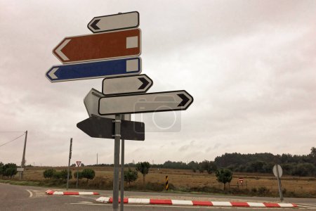 Five empty sign arrows, of different colors, point in various directions at a crossroad.