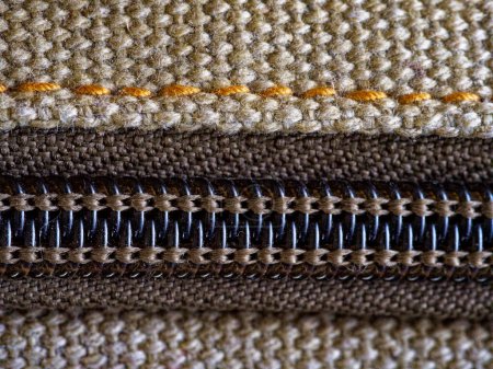 A close-up of fabric with a zipper, showing detailed stitching and texture.