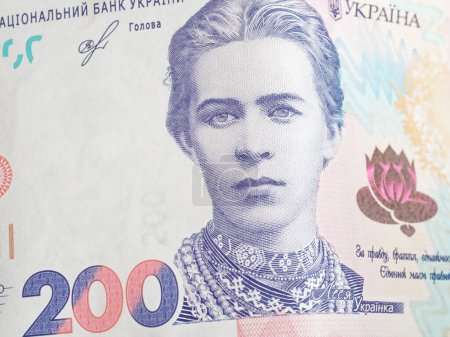 A banknote showing colorful designs, texts in Ukrainian and an facial image.