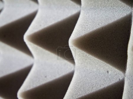 Detalle de espuma acústica. Paneles de espuma gris con diseño piramidal para control de sonido.