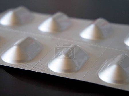 Pille Blister Detail. Großaufnahme einer Pillenblisterverpackung auf schwarzer Oberfläche, die die Pharmazie betont.