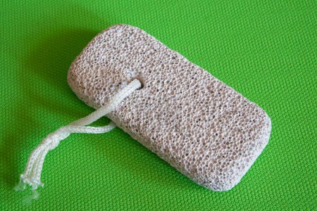 Photo for Skincare Tool Display. Pumice stone with string, presented on vibrant green, highlighting its exfoliating texture. - Royalty Free Image