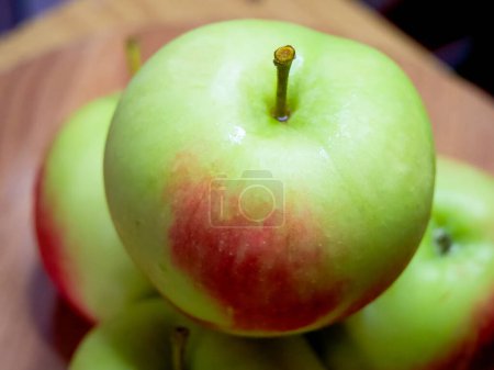 Fresh Green Apples. Crisp apples with a red blush on a wooden table.