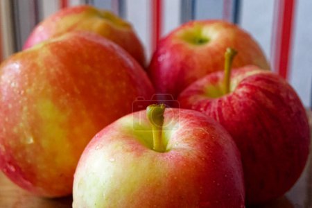 Manzanas Beso-Rocío. Manzanas frescas con rocío, vibrantes en una superficie de madera. Usos para Blogs de alimentos, artículos de salud.