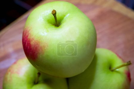 Organic Apple Display. Green apples, one in focus, on a rustic wood backdrop.