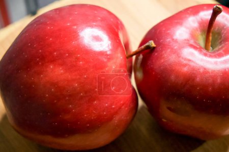 Glossy Red Apples. Two apples with stems and a white spot, symbolizing freshness.