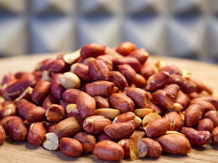 Peanuts auf Holz. Geschälte Erdnüsse auf einer Holzoberfläche verstreut, ideal für Lebensmittel und Ernährungsthemen.