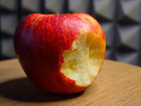 Téléchargez les photos : Pomme mordue sur bois. Une pomme rouge avec une morsure enlevée, placée sur une surface en bois, transmet fraîcheur et santé. - en image libre de droit