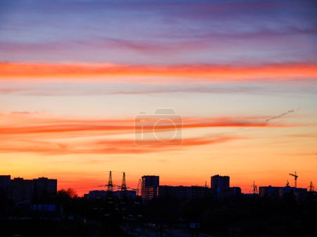 Sonnenuntergang über der Stadt mit orange-violettem Himmel, perfekt für reflektierende Stimmungen und Hintergründe.