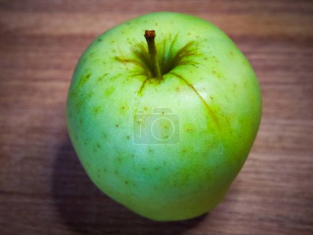 The apples smooth, shiny skin has tiny spots, showcasing natural growth.