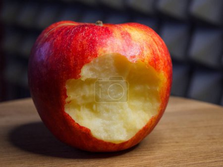 Téléchargez les photos : Pomme à la morsure. Pomme partiellement consommée sur bois, met en valeur les aliments naturels et une alimentation saine. - en image libre de droit
