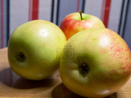 Ripe Apples on Wood. Apples with a mix of red and green hues on a wooden backdrop, perfect for food-related themes.