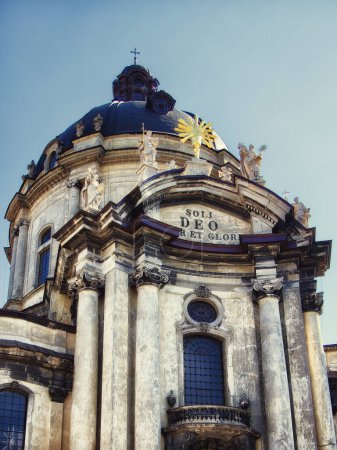 Baroque Elegance: A church facade with Latin text and a sunburst, under a clear sky. The Dominican church and monastery