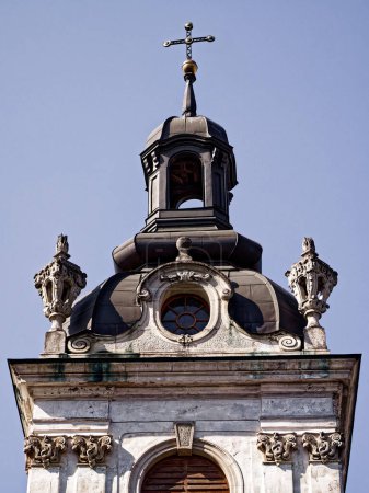 Barocker Glockenturm. Oberer Teil einer Kirche mit Glockenturm, klarer Himmel darüber, symbolisiert historische religiöse Architektur.