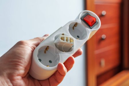 Foto de Adaptador de enchufe eléctrico en un enchufe divisor europeo en una habitación de hotel de cerca en mano turística - Imagen libre de derechos