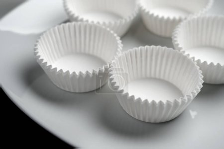 Photo for Empty unfilled paper muffin cupcake molds close up on a white - Royalty Free Image